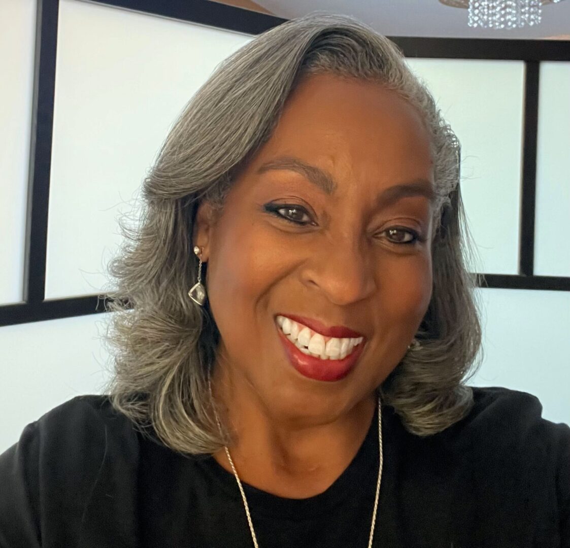 A woman with gray hair smiles for the camera.